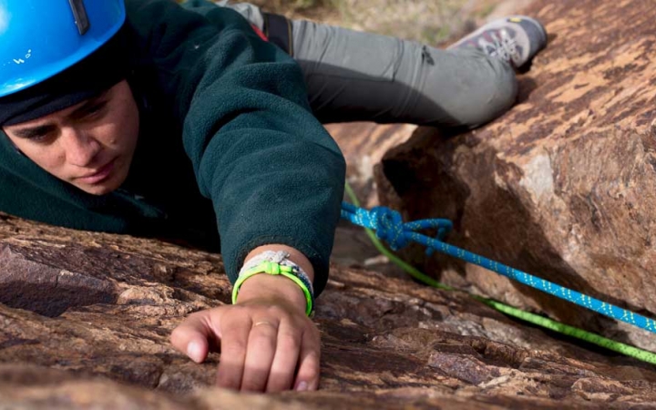 an outward bound student appears focused as they climb a rock wall in texas